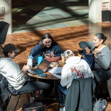 students chit chatting around a round table
