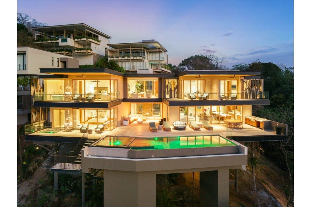 Hillside villa lit up at dusk with ocean-view terraces – Villa Zaya, Reserva Conchal, Guanacaste, Costa Rica