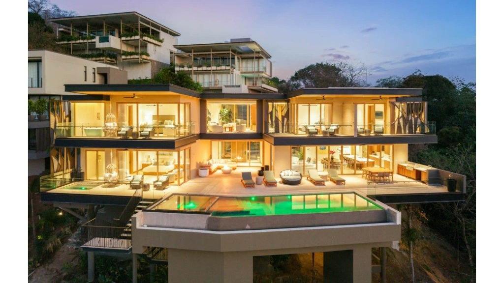 Hillside villa lit up at dusk with ocean-view terraces – Villa Zaya, Reserva Conchal, Guanacaste, Costa Rica
