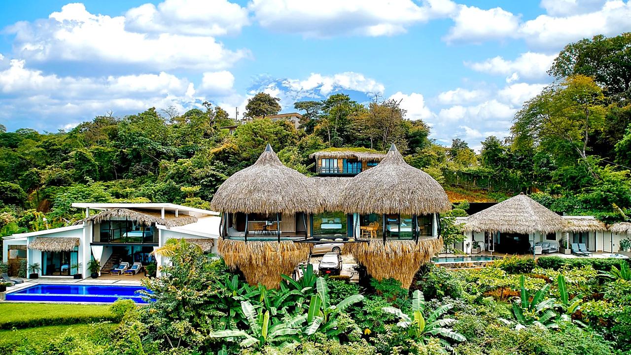 Cocoon palapa-roofed villas on the hillside with pool in the foreground
