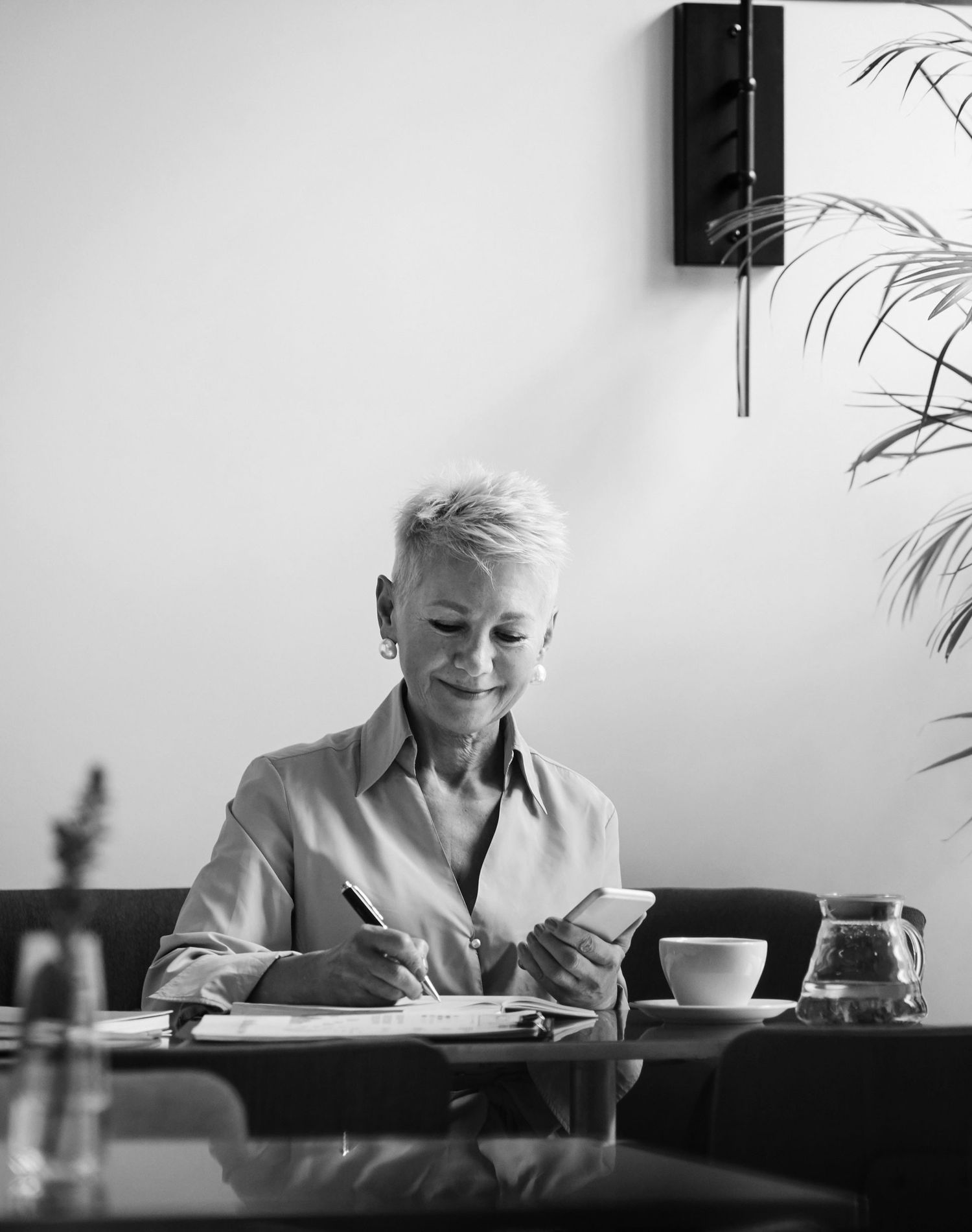 older lady smiling signing a document holding a phone