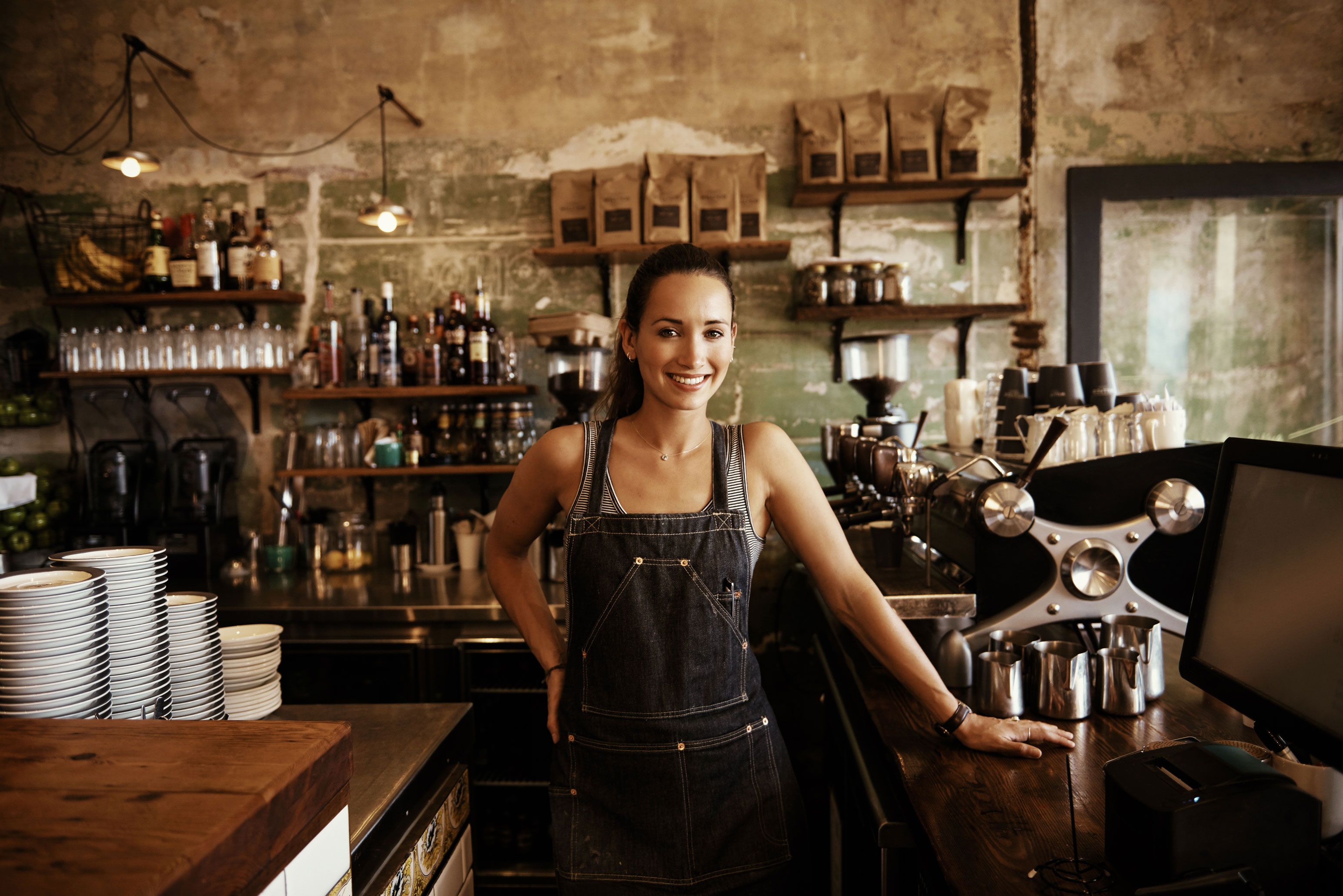 woman barista standing next to coffee machine