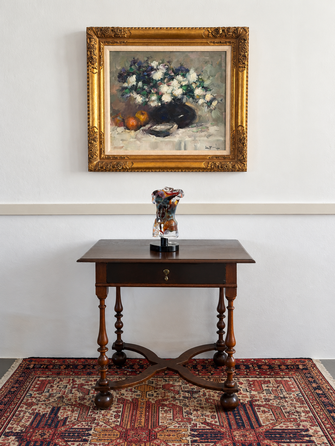 Framed floral still life above an antique table displaying a glass torso sculpture
