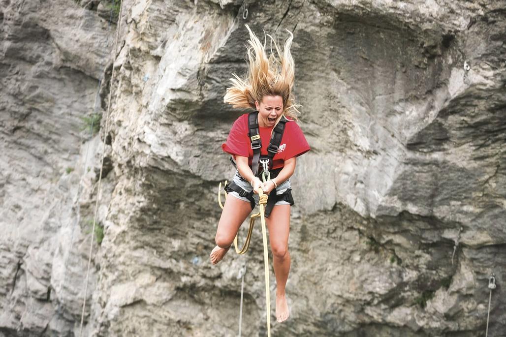 Eine junge Frau beim Sprung in die Schlucht mit der Canyon Swing