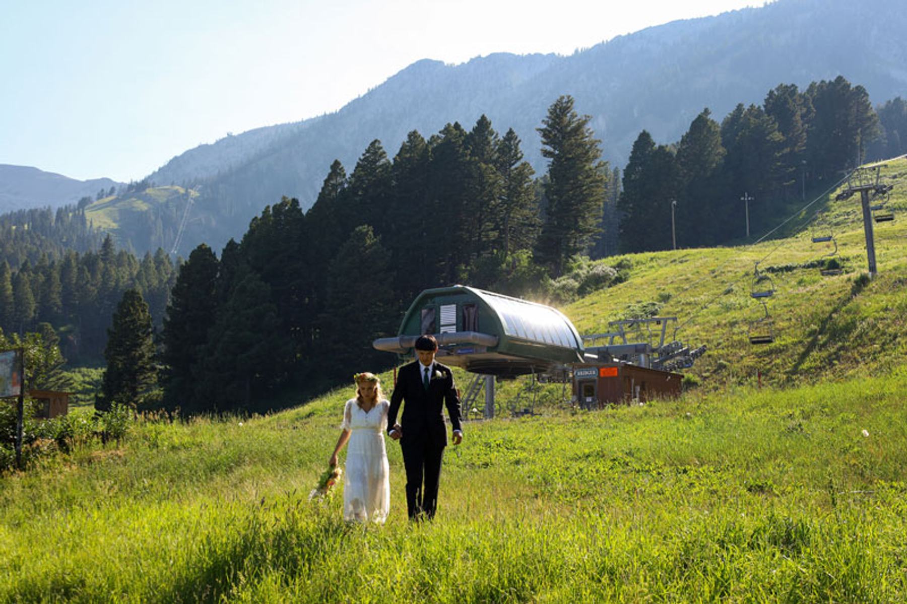 Bride and groom walking down the aisle at an outdoor mountain wedding ceremony with guests seated on both sides.