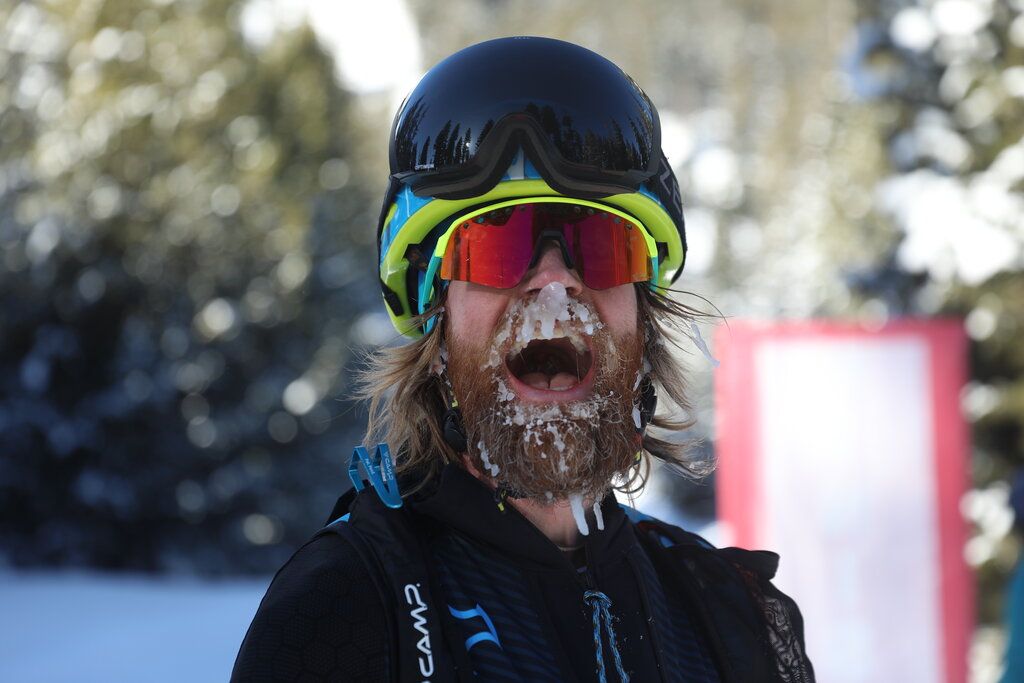 Skier with icy beard wearing helmet and goggles in the snow