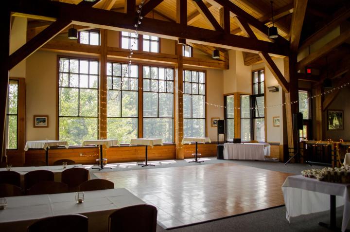 Lodge event space with exposed timber beams, dining tables, and dance floor