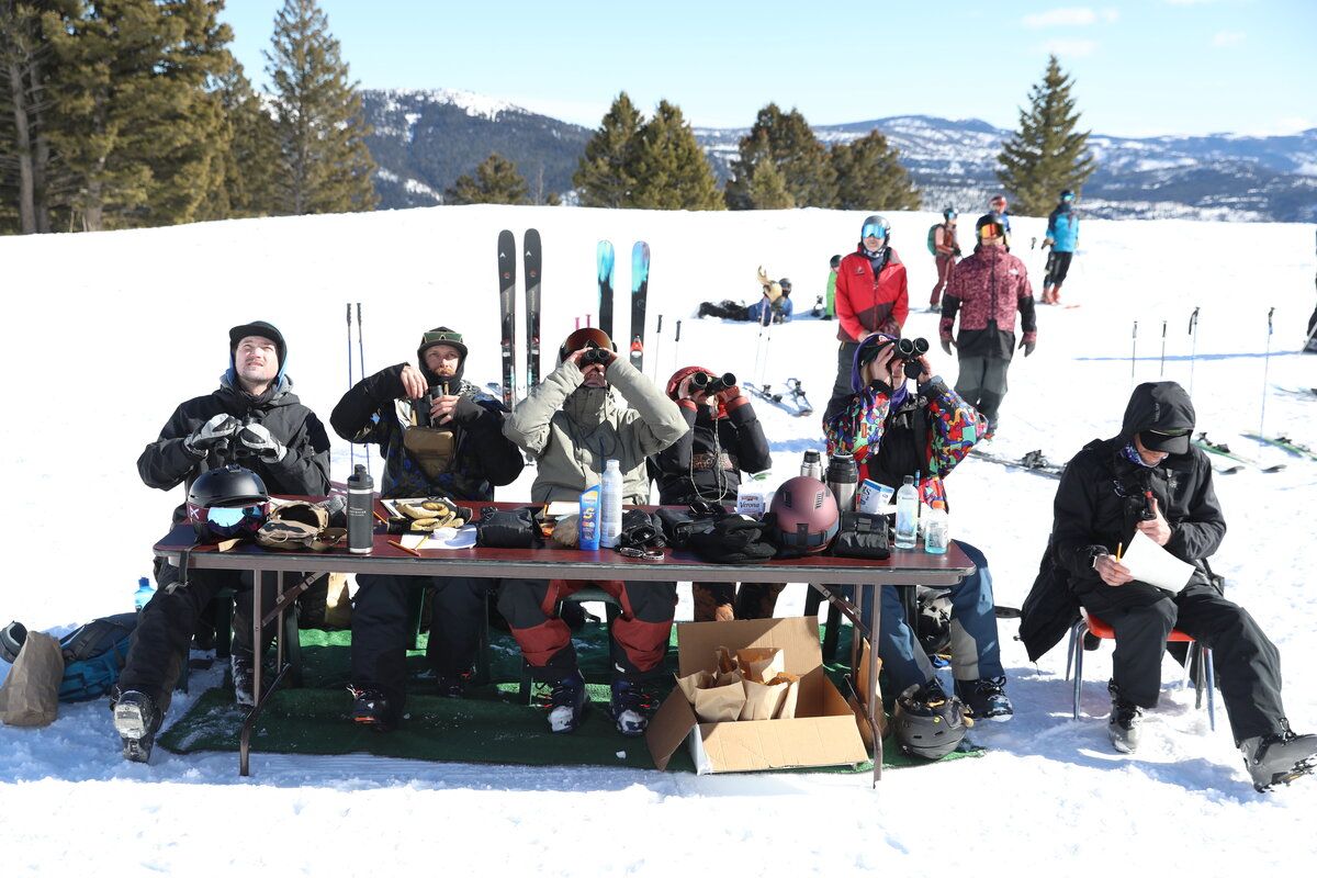 Judges seated at a table on the snow during a ski and snowboard event.