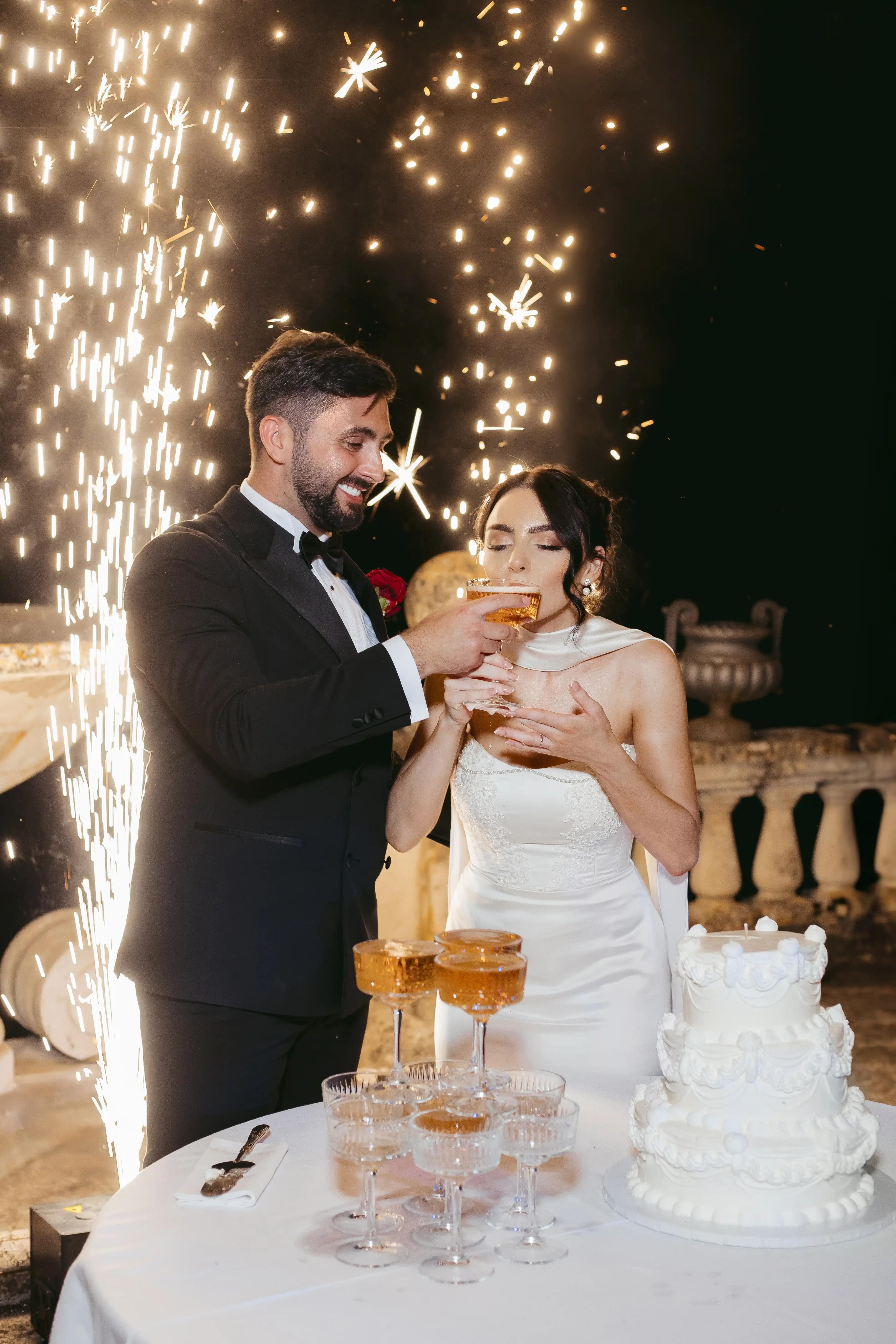 newlyweds in front of the cake with fireworks display