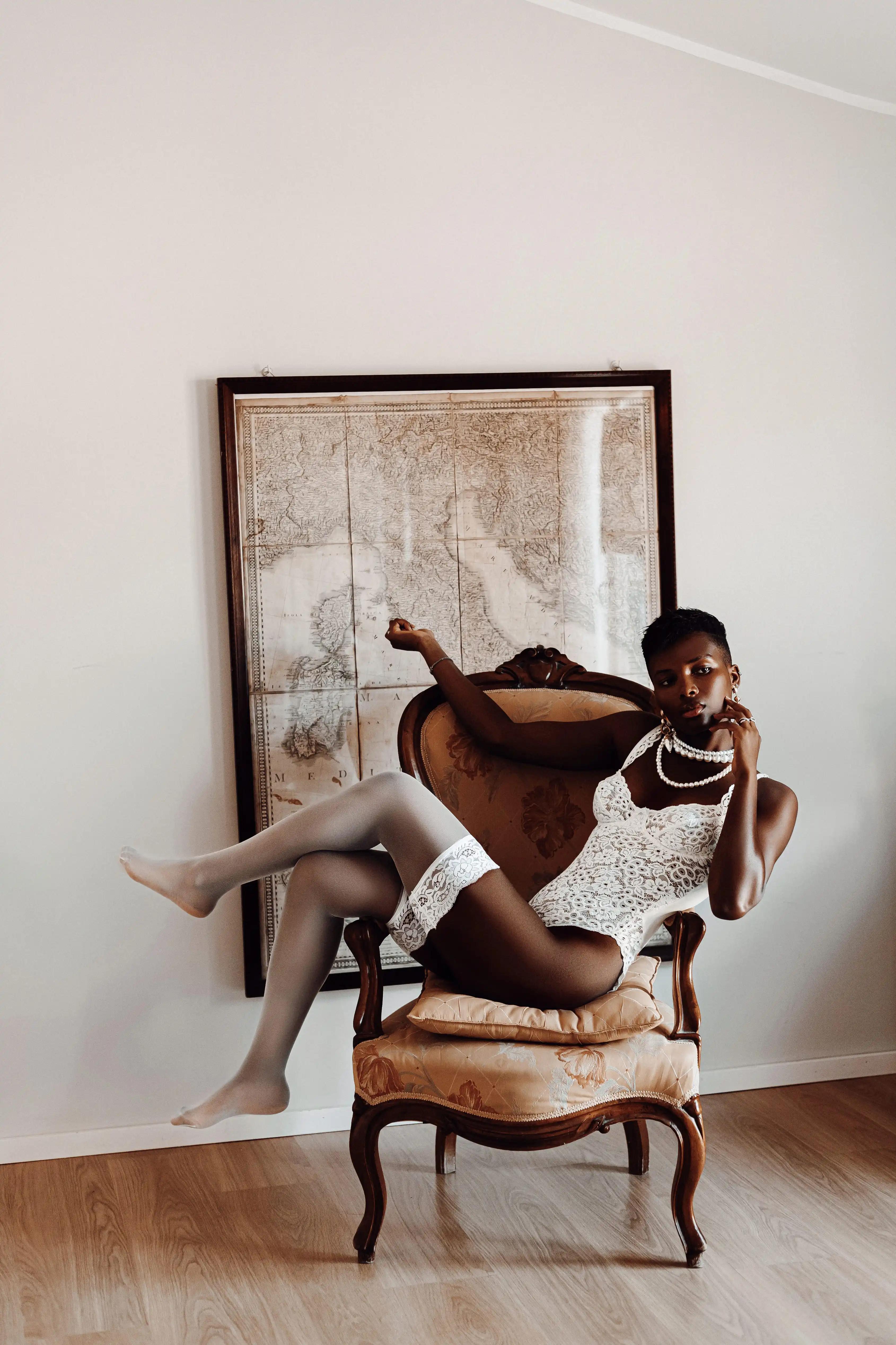Model in white lingerie lying on an armchair with a map of Italy behind her