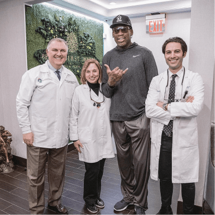 Basketball player Dennis Rodman posing with the team at Bensonhurst Dental Care