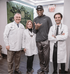 Basketball player Dennis Rodman posing with the team at Bensonhurst Dental Care