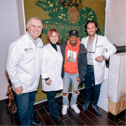 Music producer Jermaine Dupri posing with the team in front of the Bensonhurst Dental Care logo wall