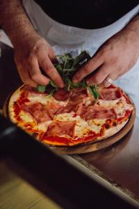 Eine Pizza wird von Hand belegt.