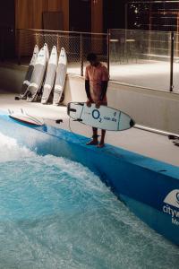 Surfer steht am Rand des Wassers mit einem Surfbrett in der Hand