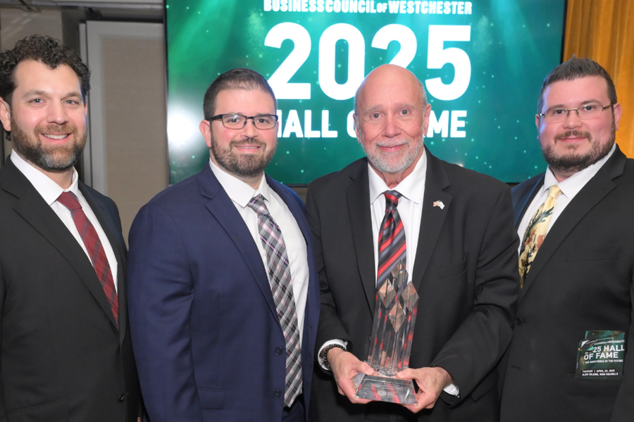 Four men in suits pose with a glass award in front of a green Business Council of Westchester backdrop reading "2025 Hall of Fame."