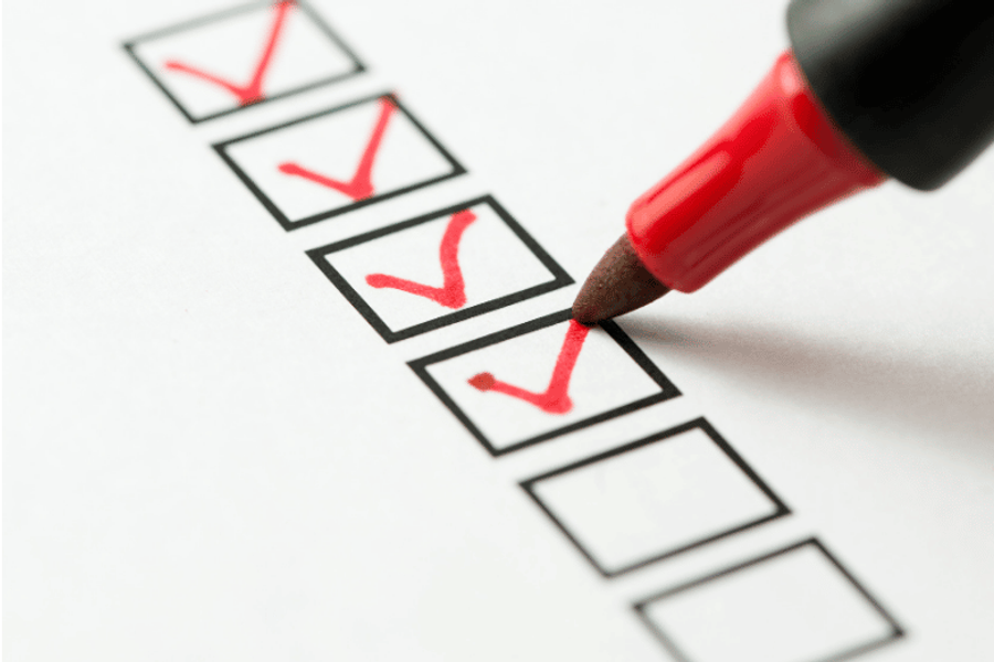 Close-up of a red marker checking off boxes on a printed checklist, with four boxes marked and two left blank.