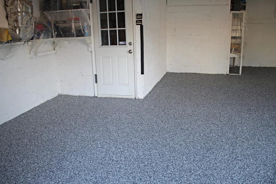 Garage interior with a new gray flake floor coating, white-painted block walls, and a white nine-pane entry door.