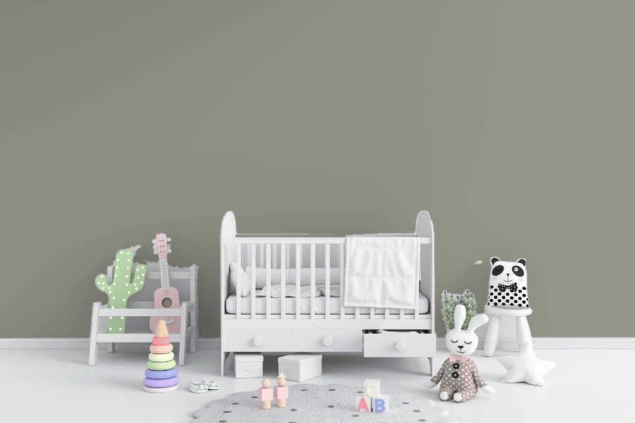 Nursery with a soft sage-green wall behind a white crib, plush panda and bunny toys, a small pink guitar, and pastel stacking toys on the floor.