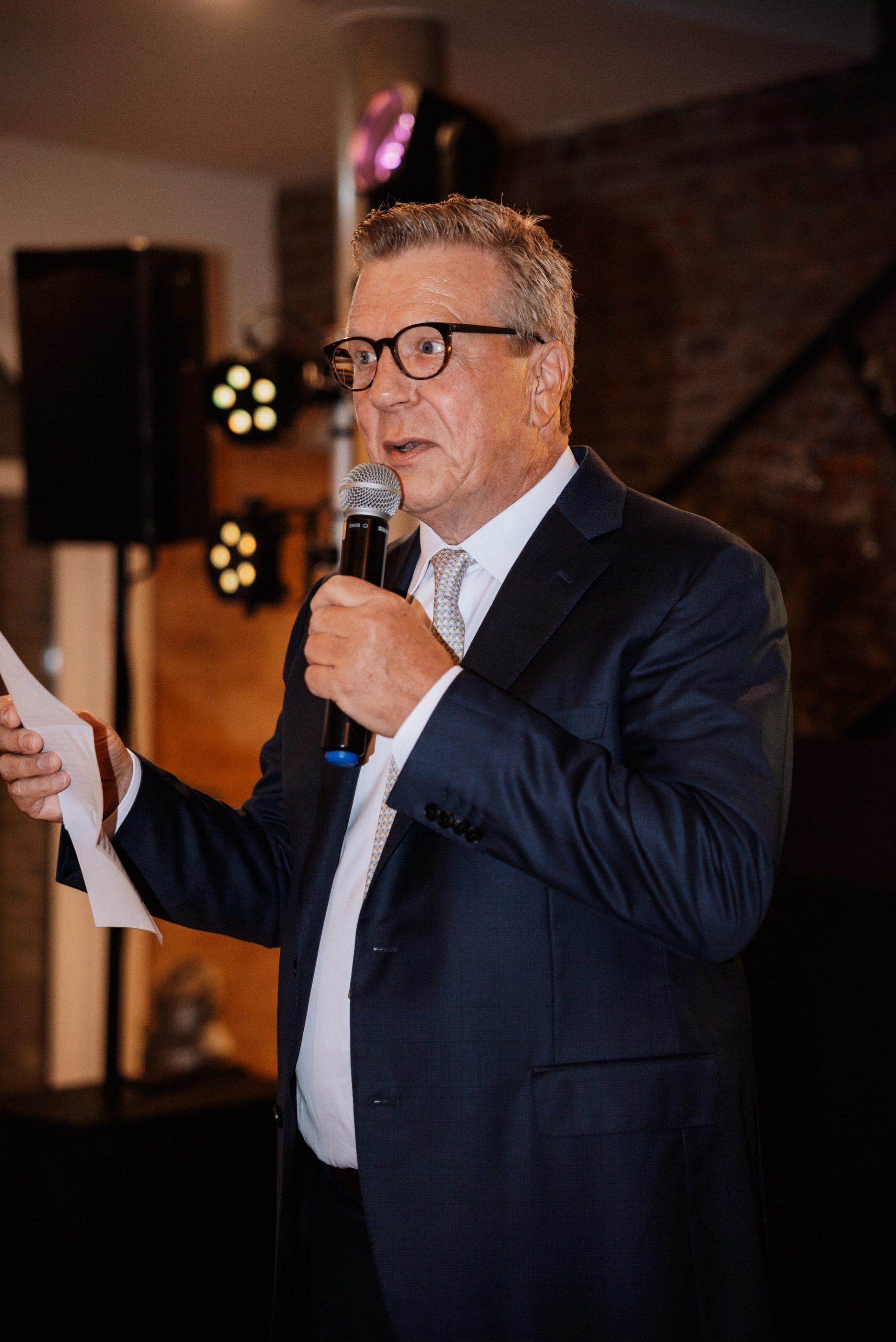 Ein Gast hält am Abend eine Rede mit Mikrofon und Zettel