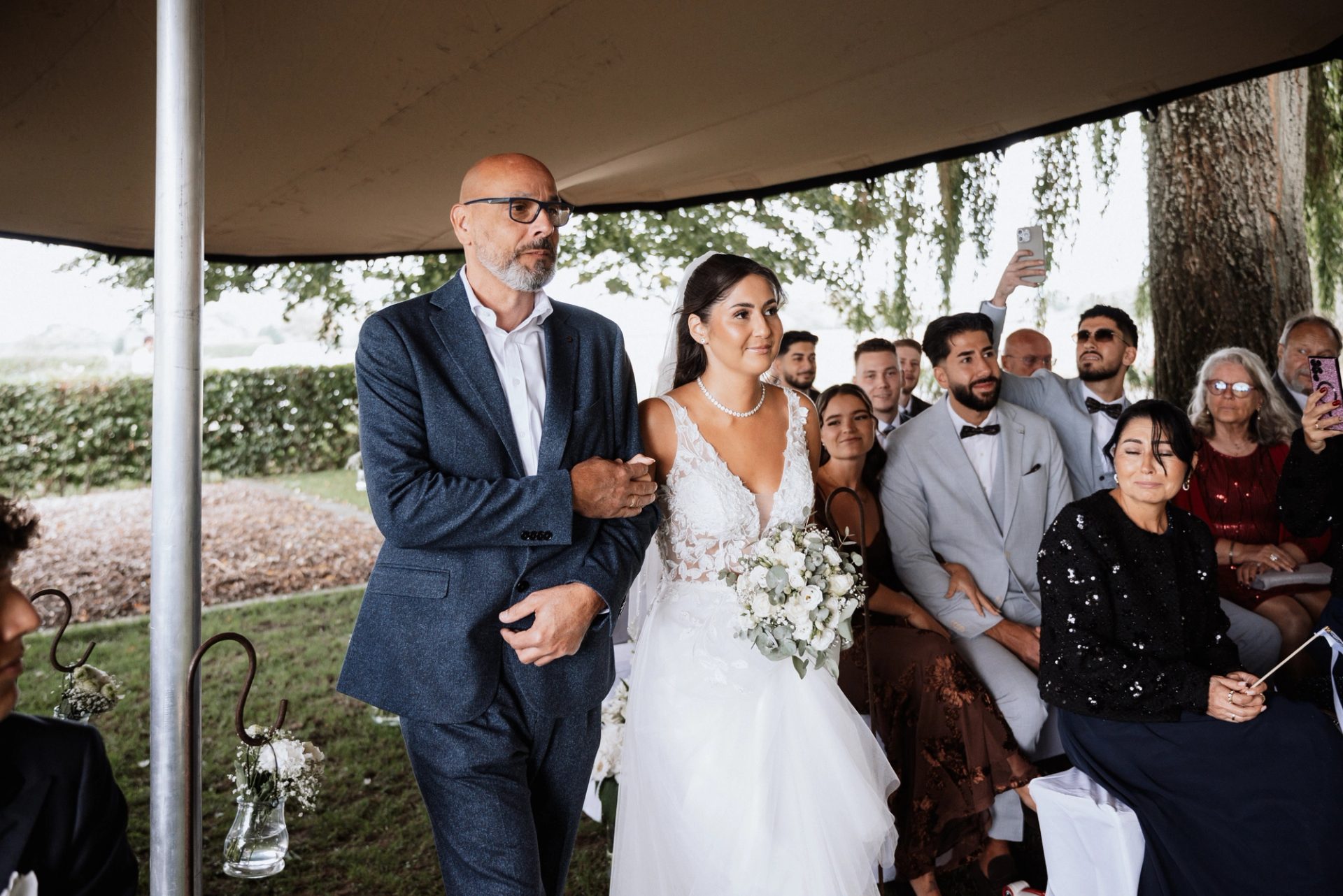 Merve geht mit ihrem Vater an den Stühlen der Gäste vorbei