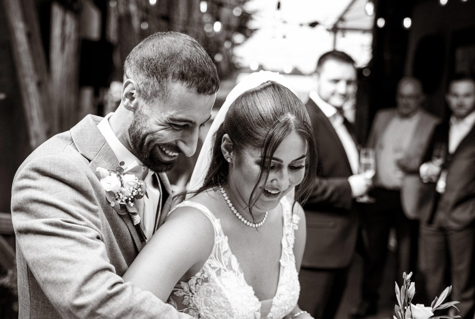 Timur und Merve lachen beim Anschneiden der Torte, in Schwarzweiß
