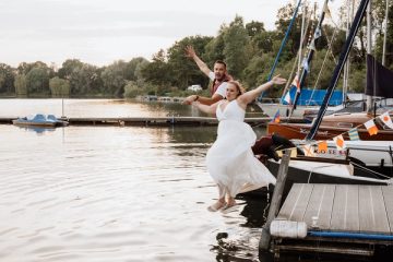 Claudia springt im Brautkleid mit ausgebreiteten Armen in den See