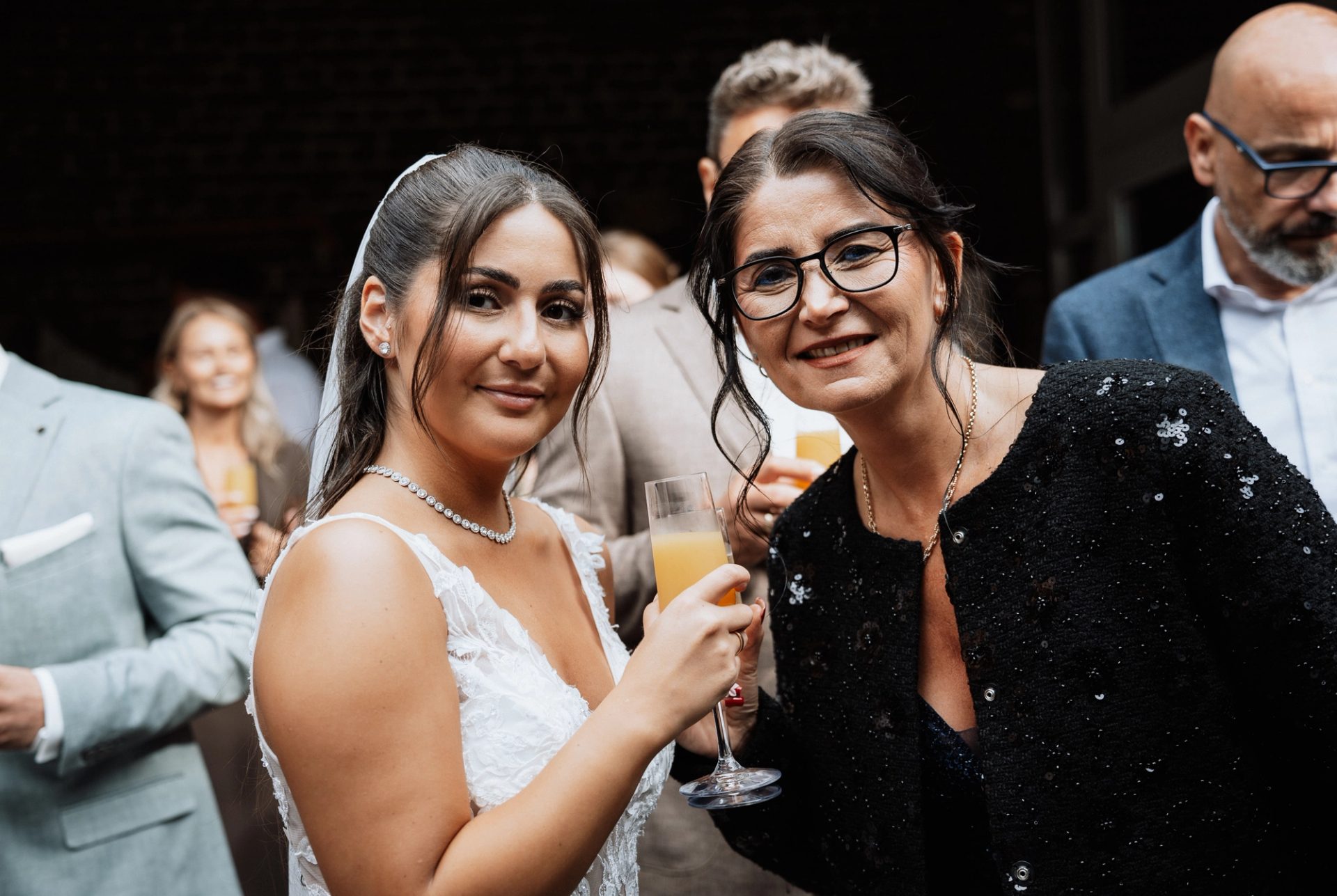 Merve mit einem Glas Sekt neben einer Frau mit Brille