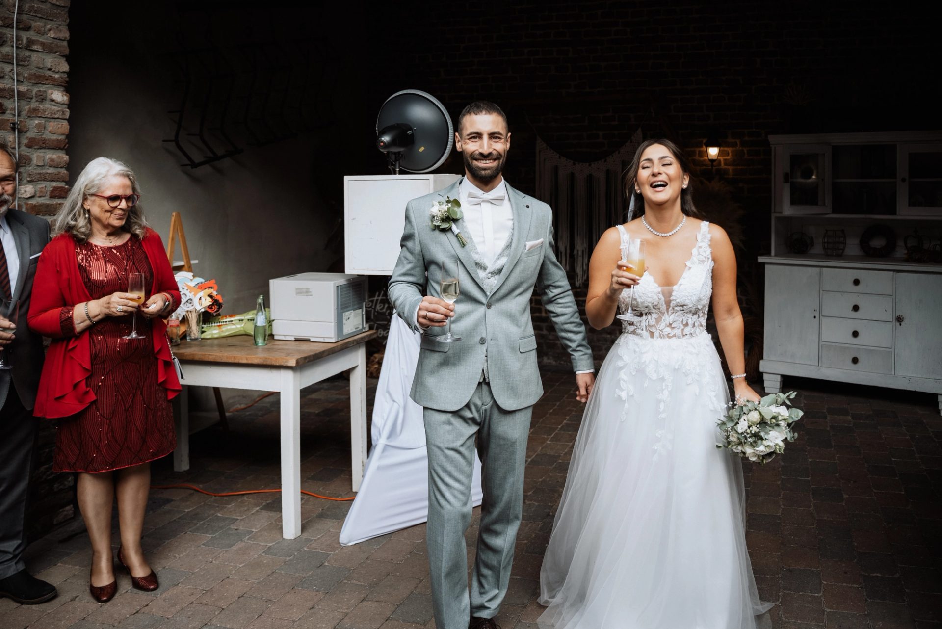 Merve und Timur kommen lachend mit ihren Gläsern in den Innenhof
