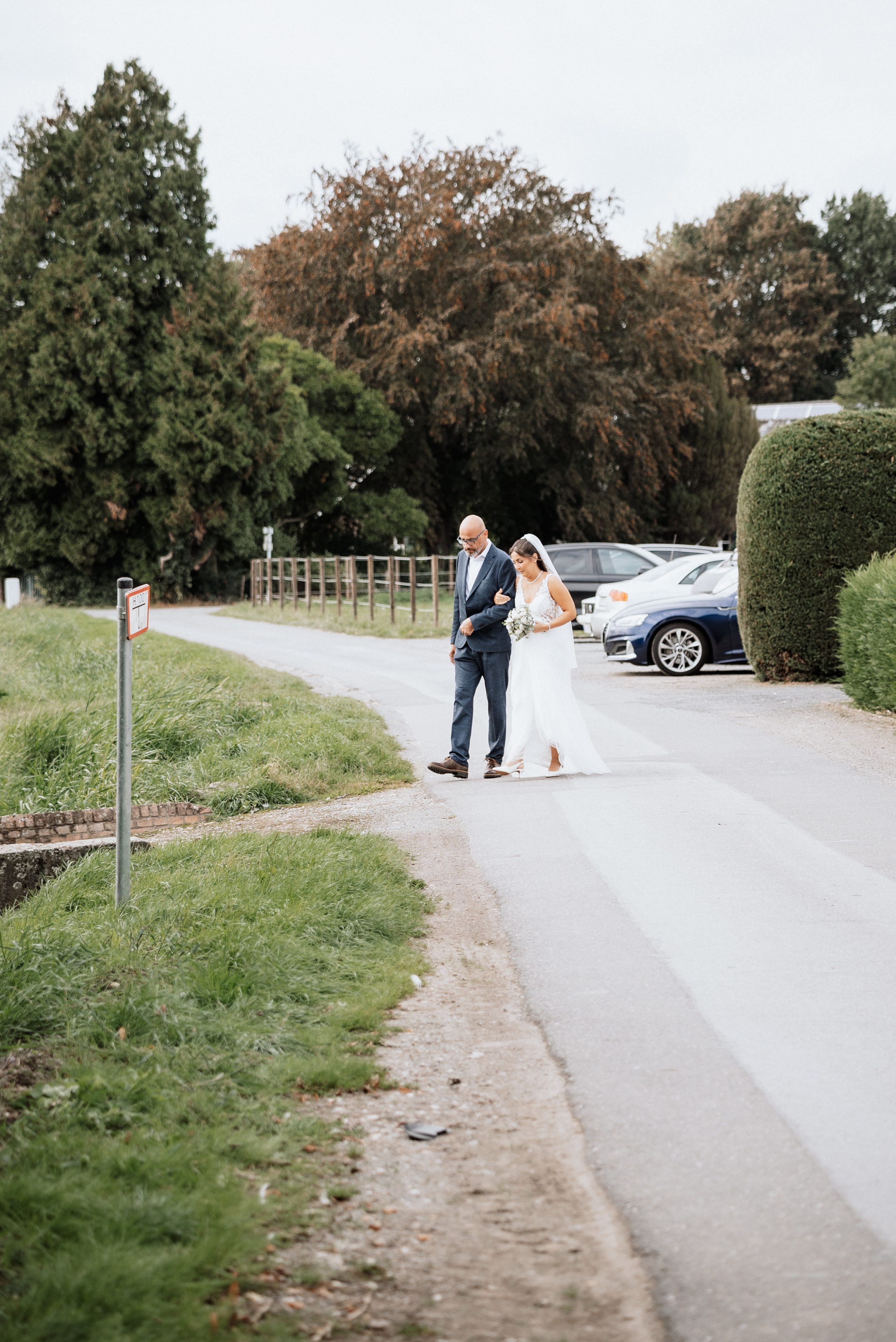 Merve kommt am Arm ihres Vaters den Weg zur Trauung entlang