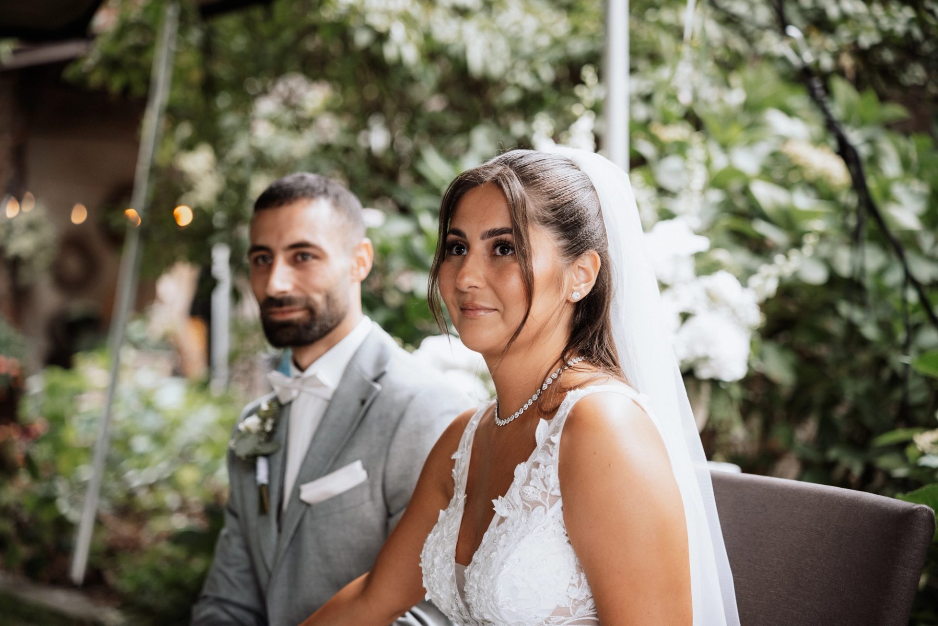 Merve und Timur sitzen nebeneinander und lächeln bei der Trauung