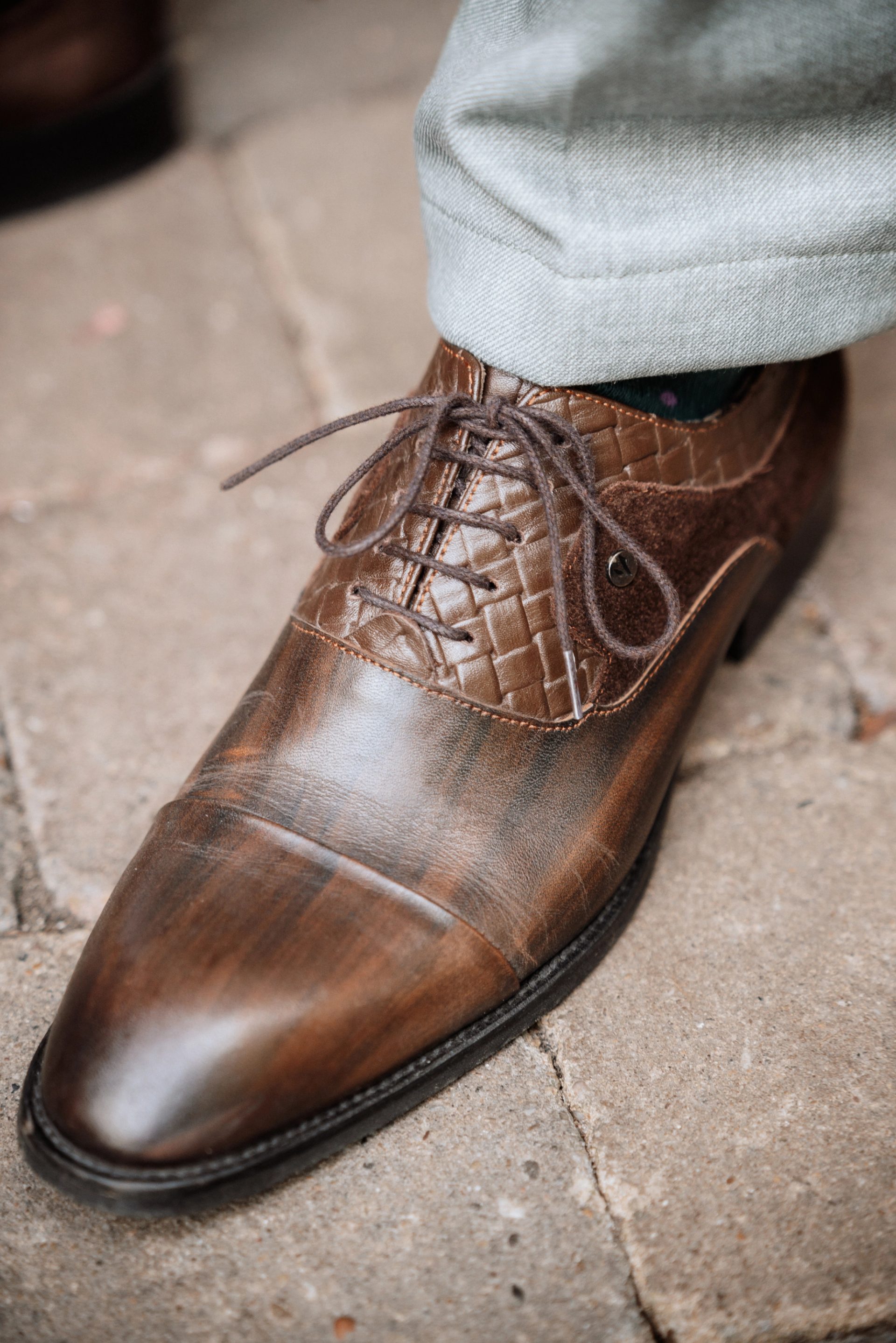Die braunen Lederschuhe des Bräutigams auf dem Pflaster