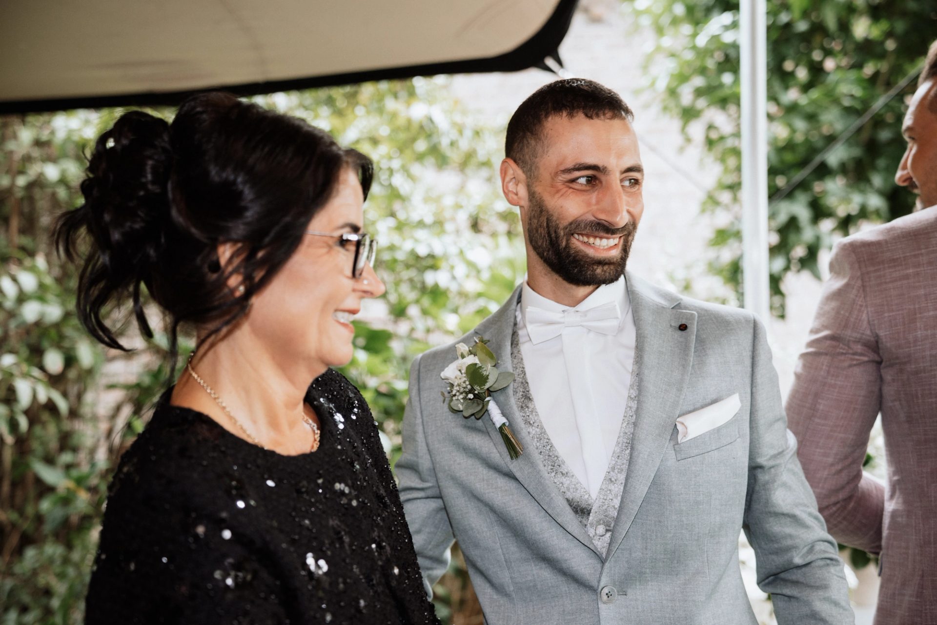 Timur strahlt, eine Frau im glitzernden Kleid gratuliert ihm