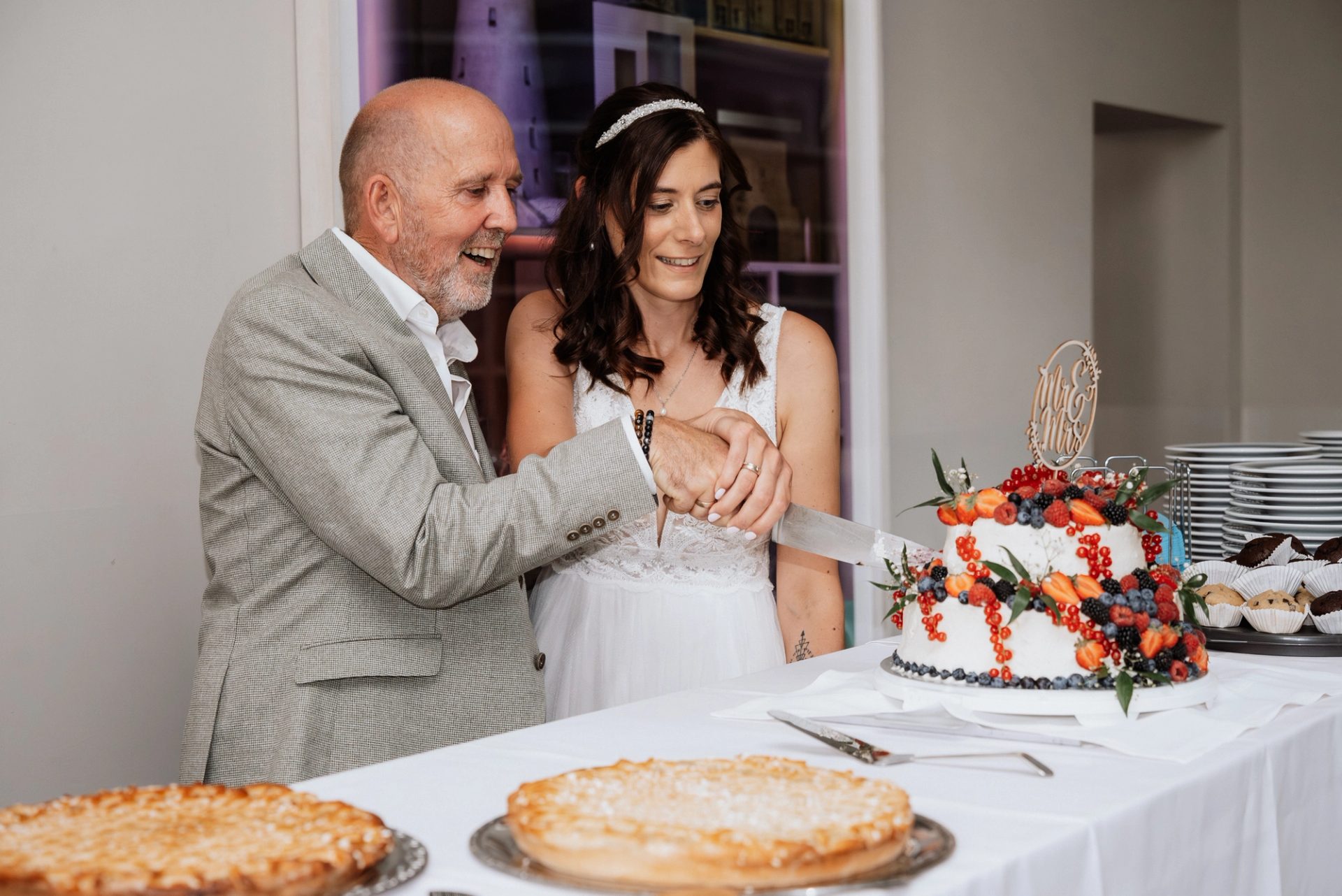Ralph und Maren halten das Messer an der Torte mit frischen Früchten