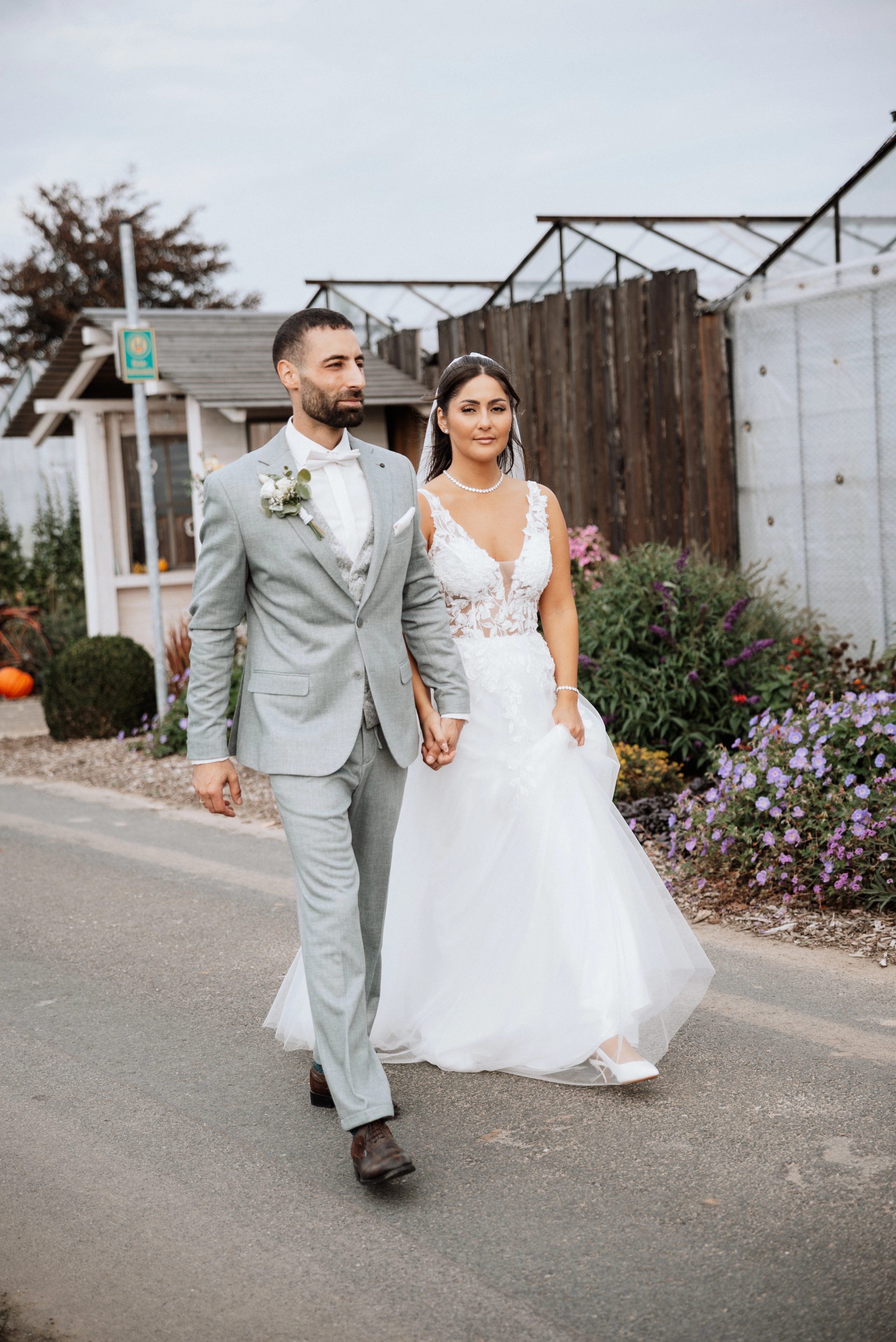 Merve und Timur gehen einen Weg zwischen Gewächshäusern entlang