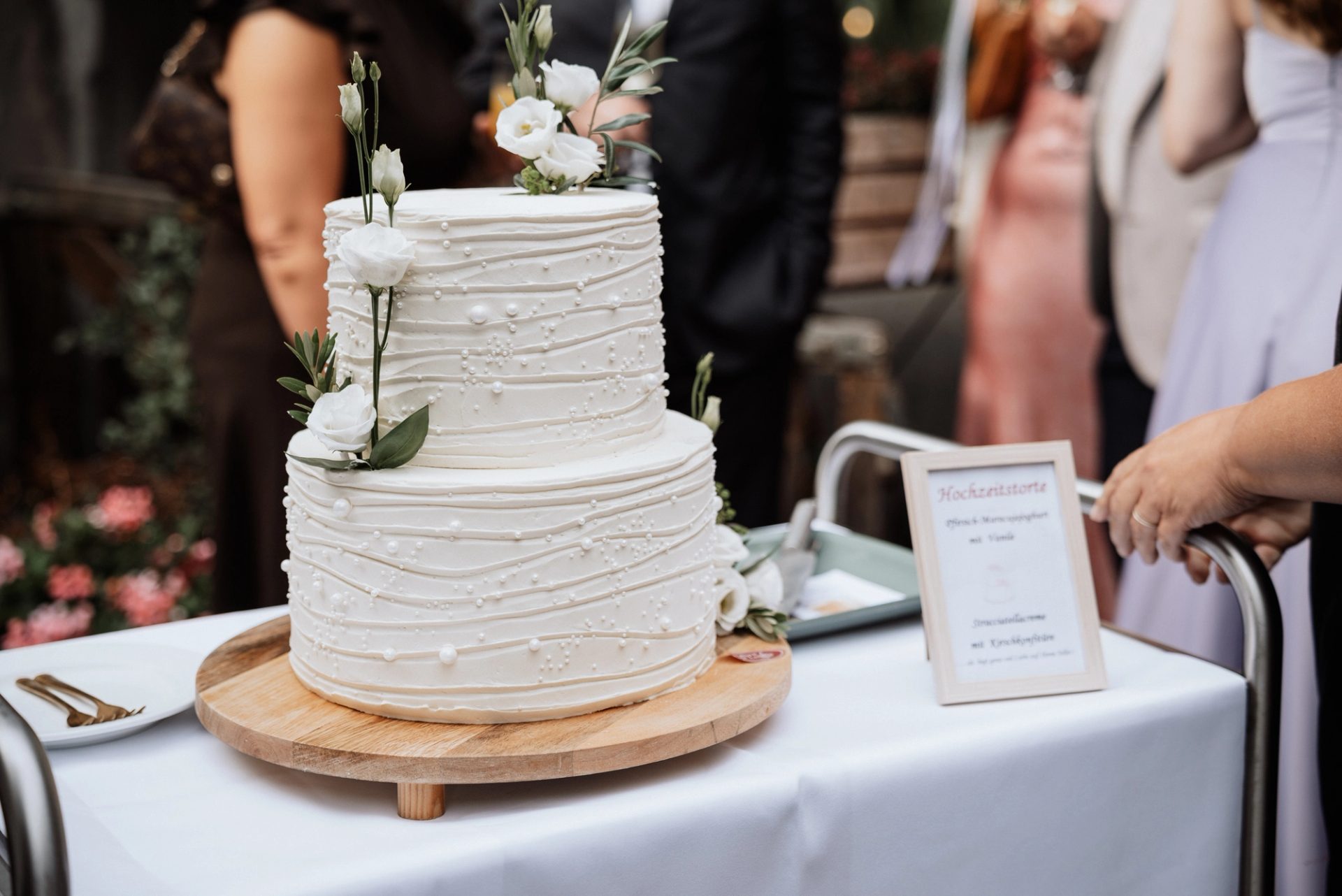 Die weiße, zweistöckige Hochzeitstorte mit Blüten