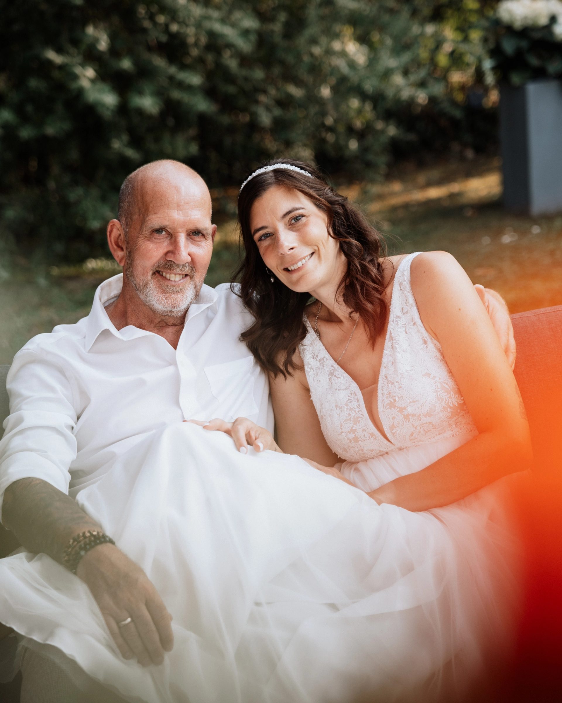 Maren und Ralph lächeln in die Kamera, am Bildrand ein orangefarbener Lichtschein