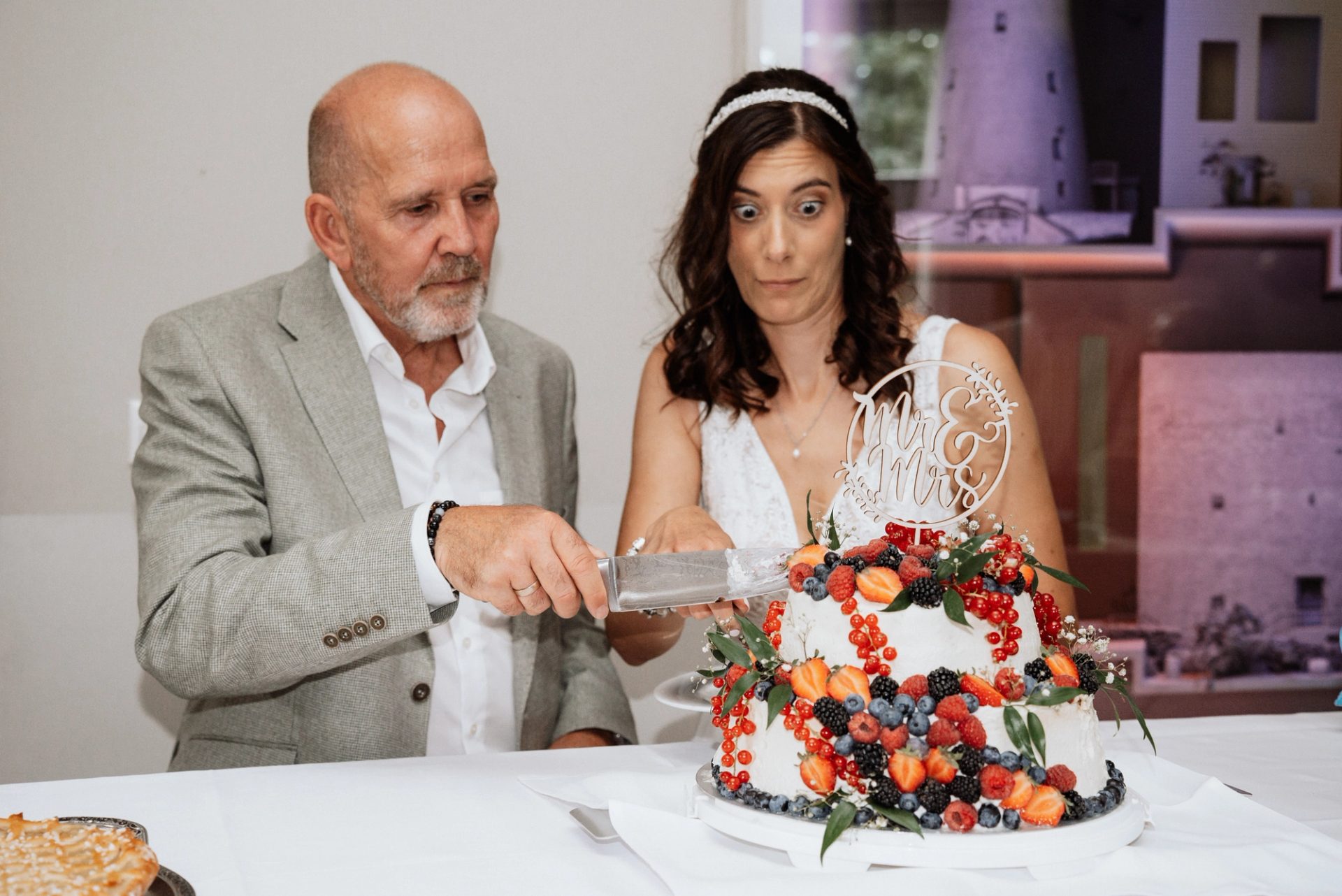 Nahaufnahme: Ralph und Maren mit dem Messer an der Torte, obendrauf ein Tortenaufsatz