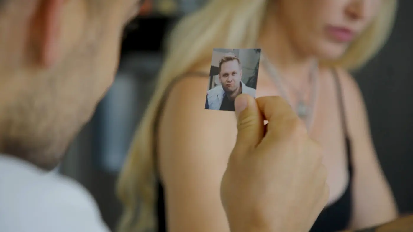 A hand holds a small photo of Ben Lister during the spell, with Nina blurred behind