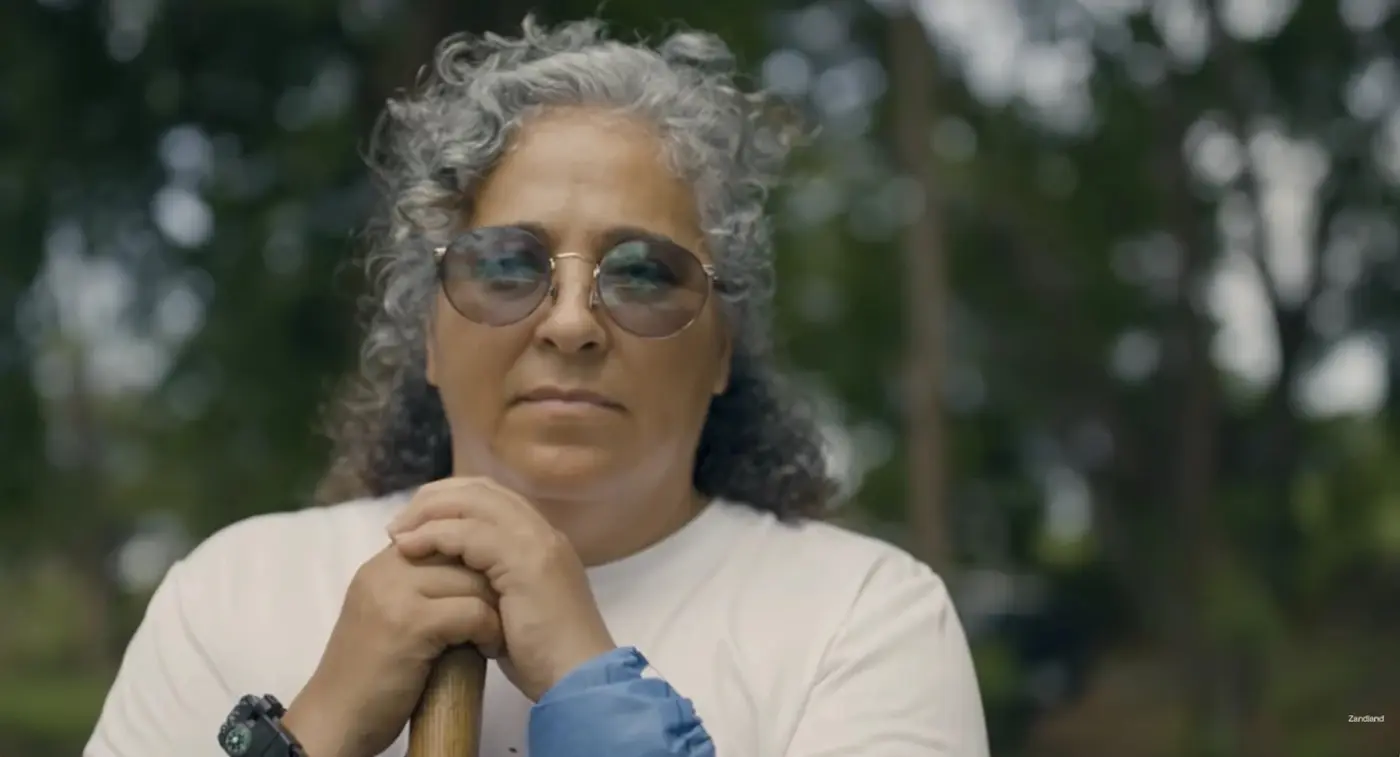 Maria, who searches for missing people in Mexico, with her hands resting on the handle of a shovel