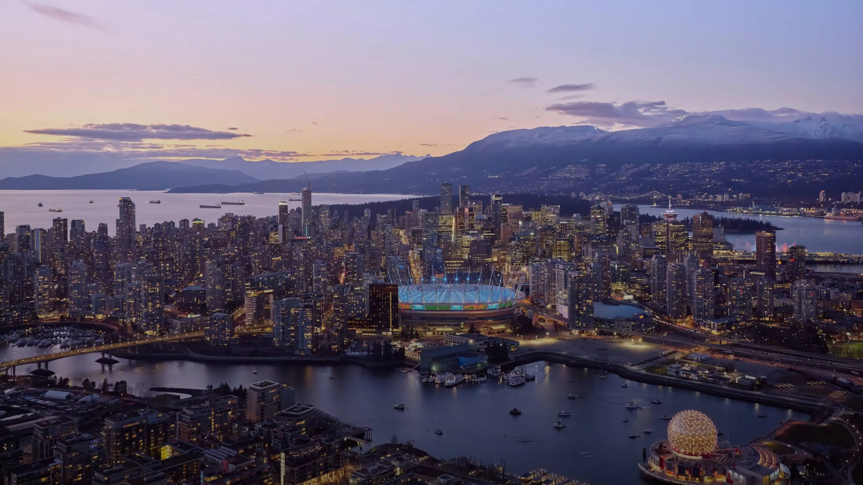 An arial shot of Vancouver shows BC Place on one side of the water and Science World on the other.