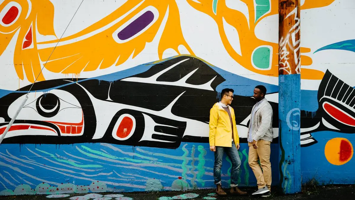 Two men talking in front of a mural in Mount Pleasant at the Vancouver Mural Festival