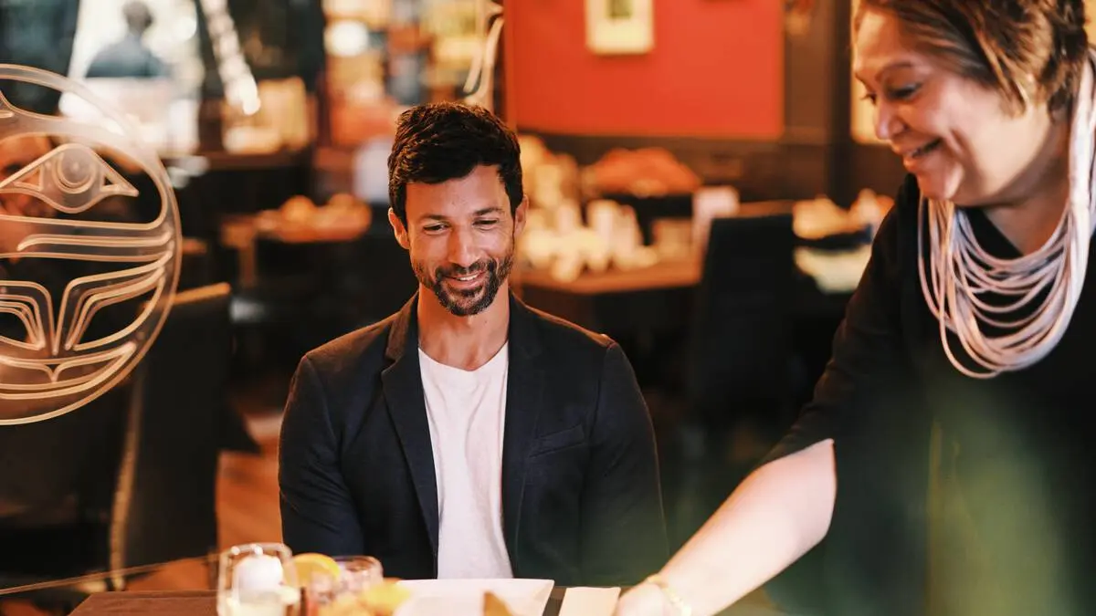 Inez Cook, the owner of Salmon n' Bannock in Vancouver, serves food to a couple at the restaurant.