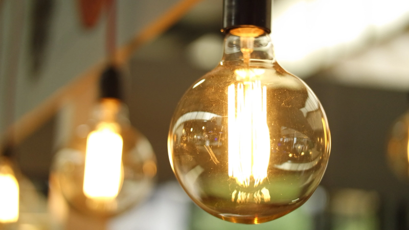 A close-up of a warm colored light bulb hanging indoors.