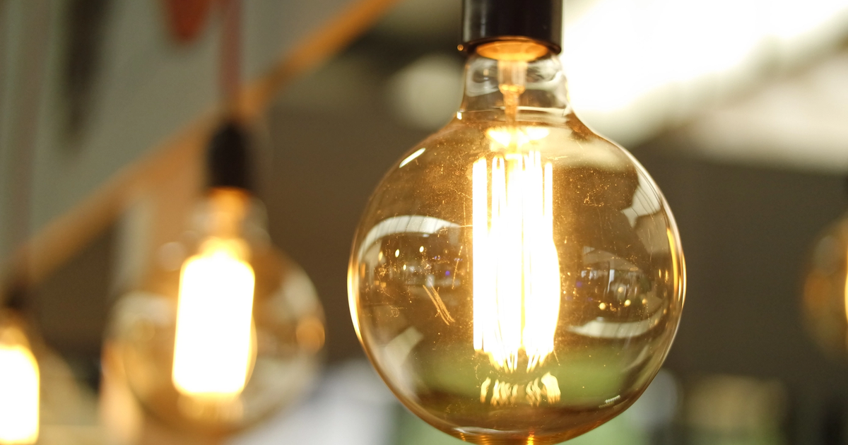A close-up of a warm colored light bulb hanging indoors.