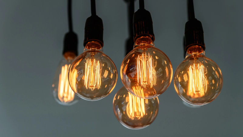 Warm, glowing vintage light bulbs with intricate filaments, inviting light against a soft gray backdrop.