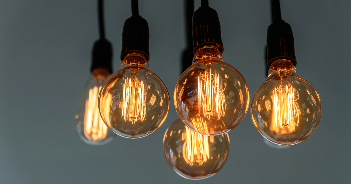 Warm, glowing vintage light bulbs with intricate filaments, inviting light against a soft gray backdrop.