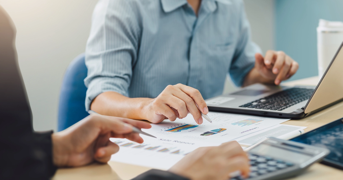 Small business owners reviewing their cash flow while using a laptop and a calculator.