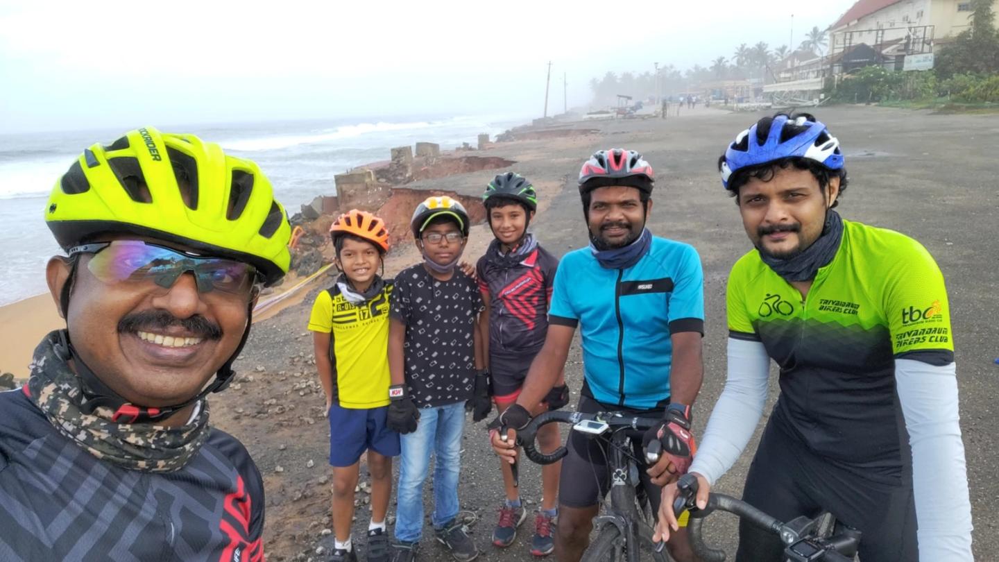 Children and adult cyclists posing beside the beach.