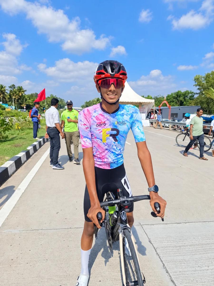 Juan Joy at a road race in his race number, smiling beside his road bike